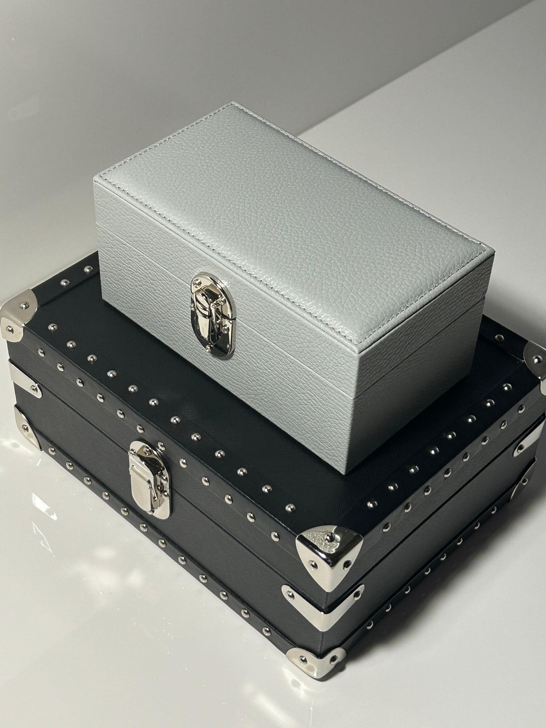 Two luxury Italian leather jewelry boxes with metal clasps and studded trim on a white surface