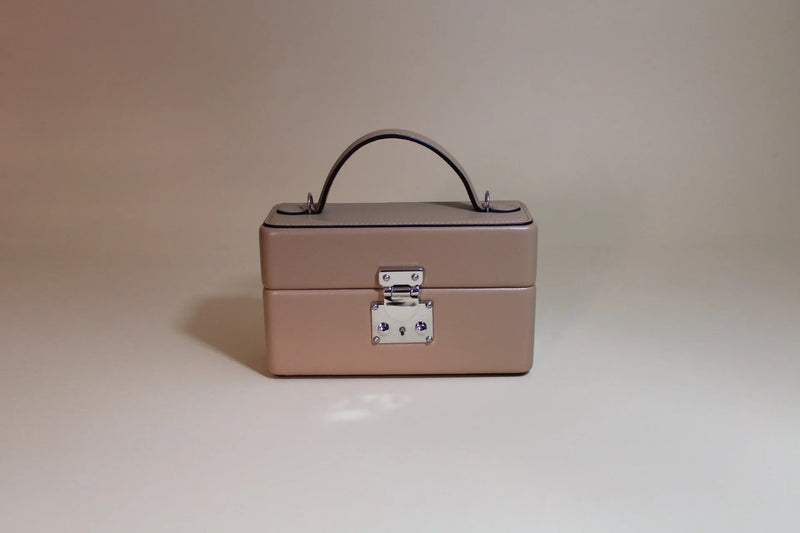 Beige leather box-shaped handbag with top handle and silver clasp, minimalist background