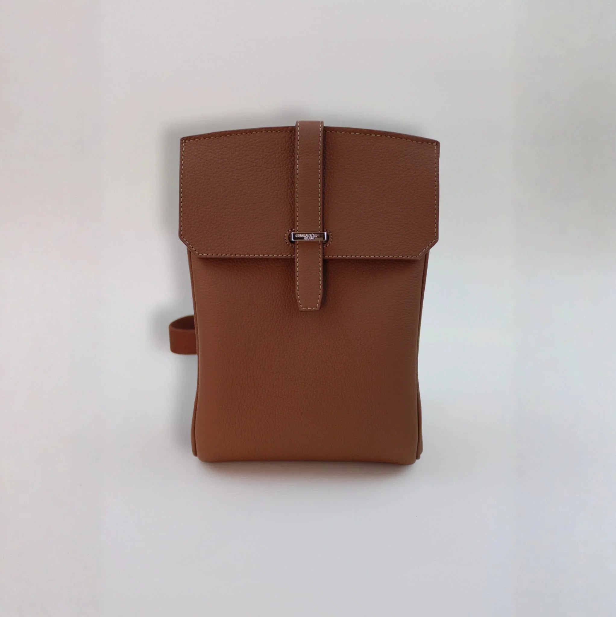 Brown Italian leather backpack with flap closure and minimalist design on white background