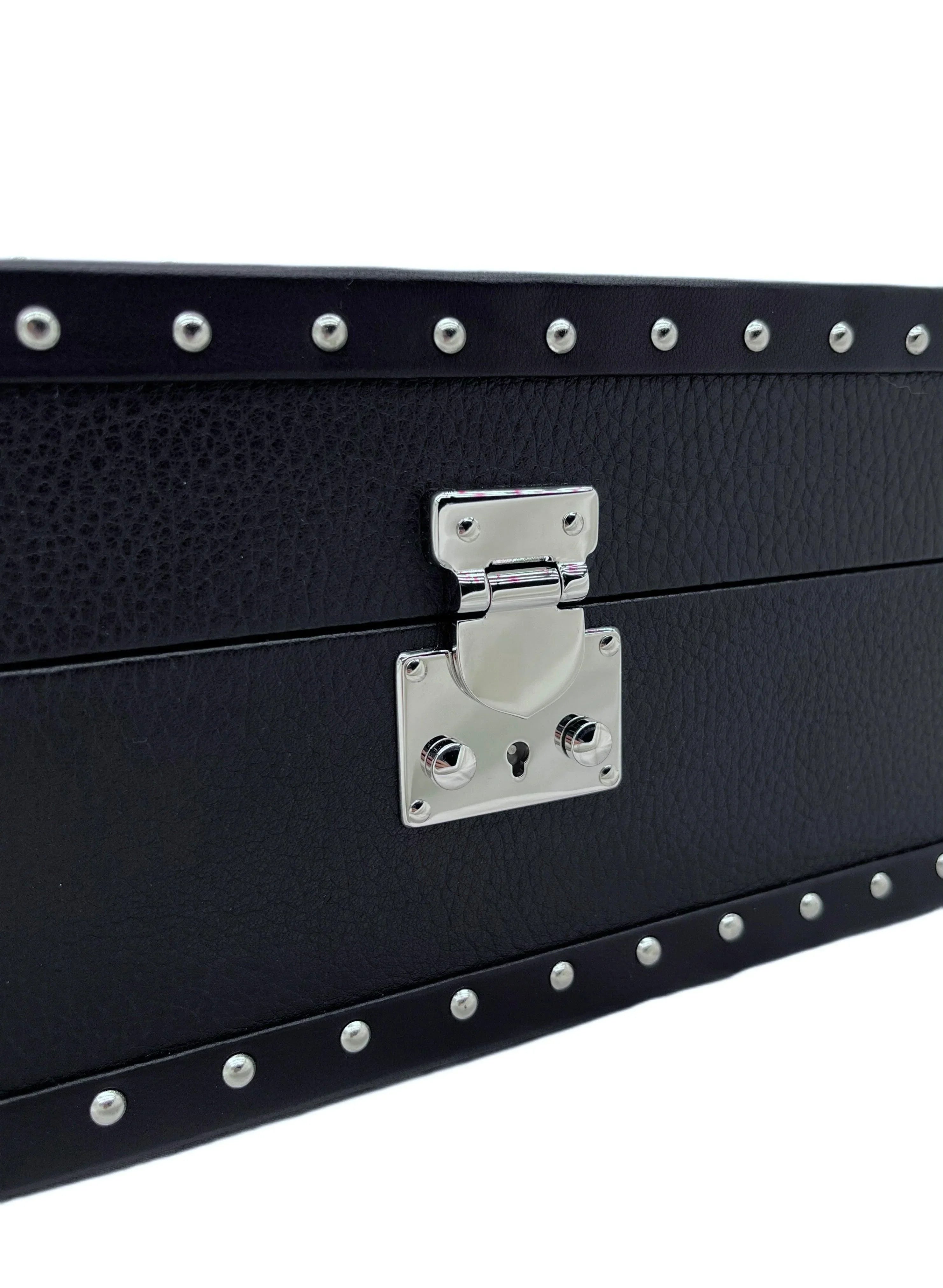 Close-up of black textured leather box with silver studs and polished metal latch