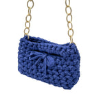 Blue crochet handbag styled on shoulder with gold chain strap