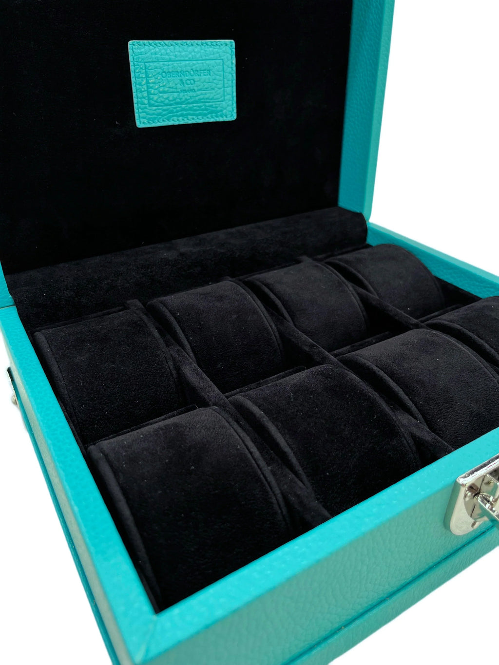 Turquoise leather luxury watch box with black velvet interior and multiple compartments.