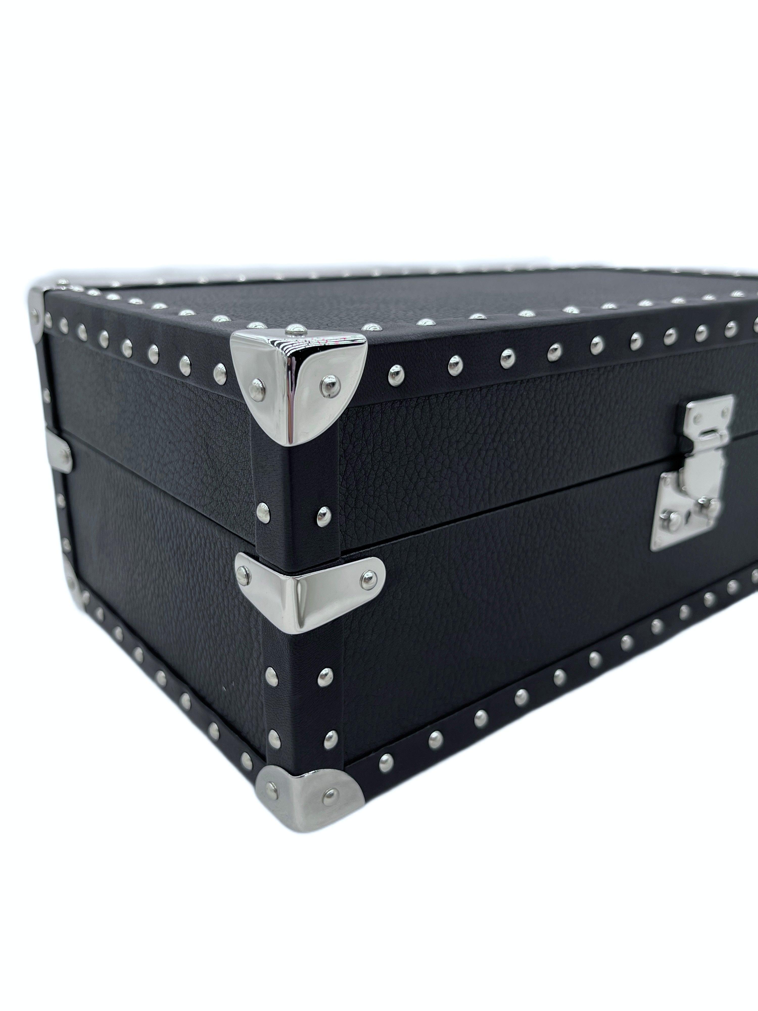 Black leather luxury storage box with silver metal studs and corner hardware, close-up view