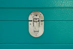 Close-up of silver clasp on turquoise textured leather case, luxury accessory detail