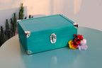 Turquoise leather box with metal corners on a table, flowers beside it, modern setting