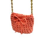 Peach mini crochet handbag styled on shoulder with gold chain strap