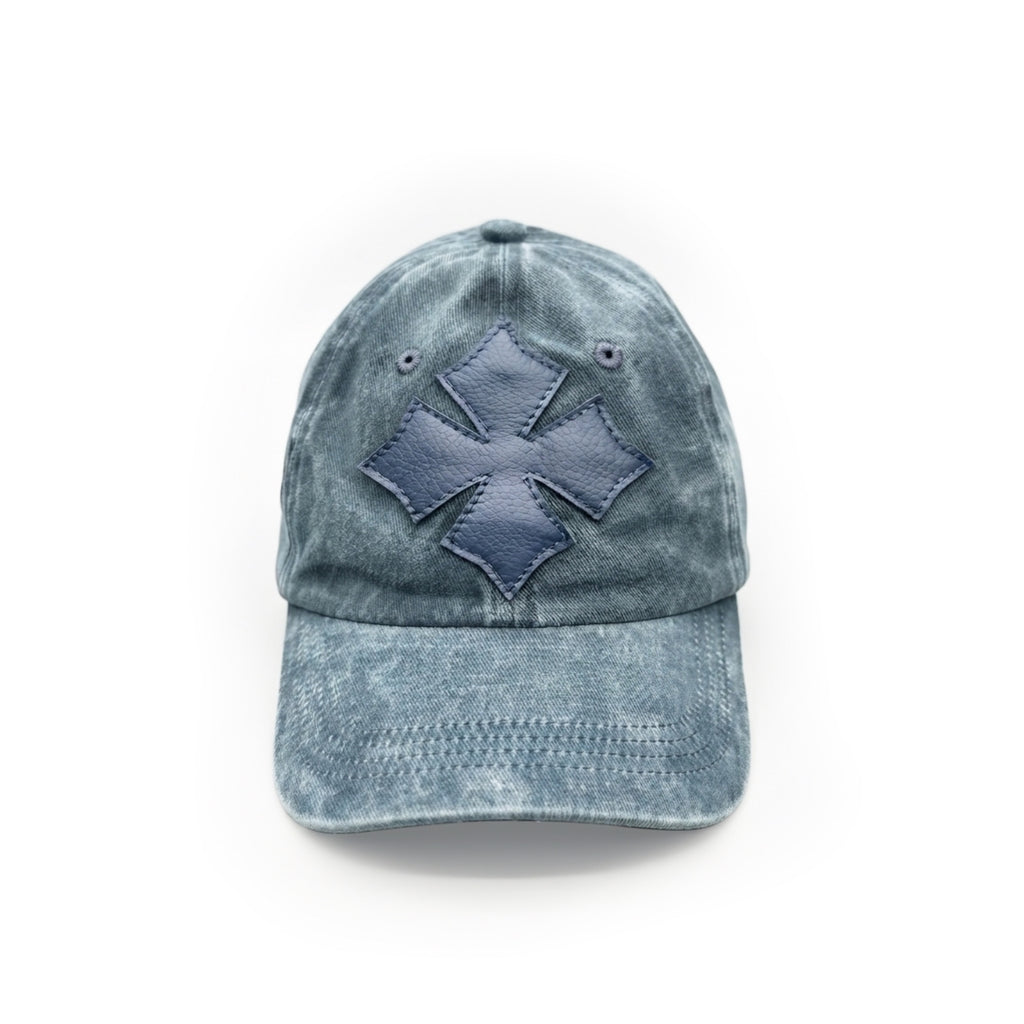 Three-quarter view of the blue washed cotton cap showing the calf leather logo patch and crown seams