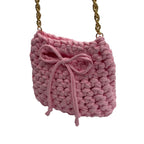 Pink mini crochet handbag styled on shoulder with gold chain strap