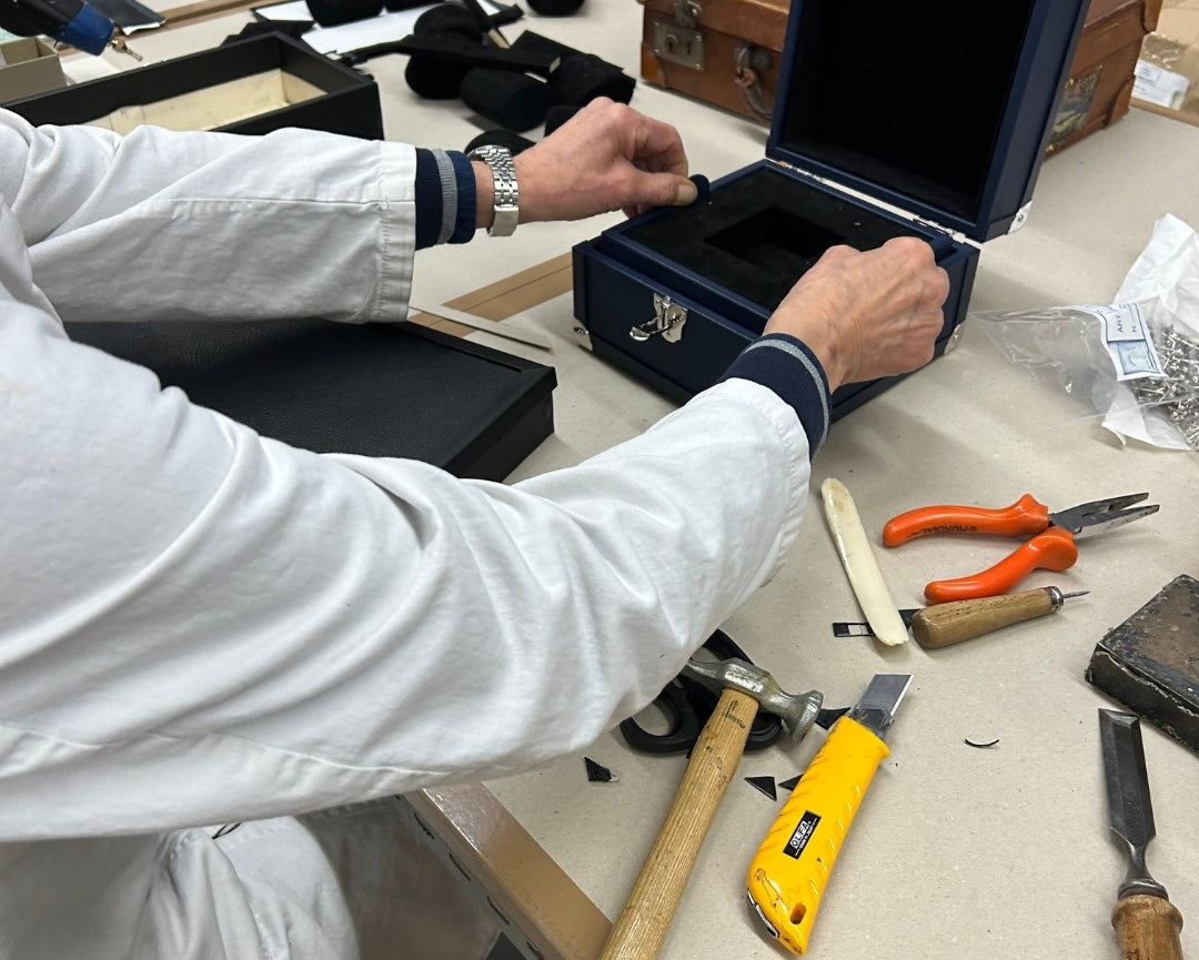 Person working on watchbox with various tools on a workbench
