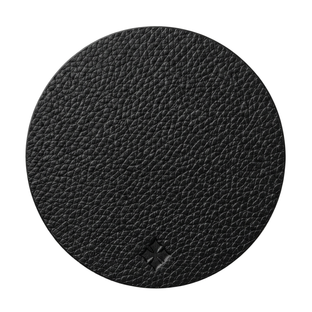 A round black textured leather coaster or mat with a pebbled leather grain finish, shown on a solid white background.