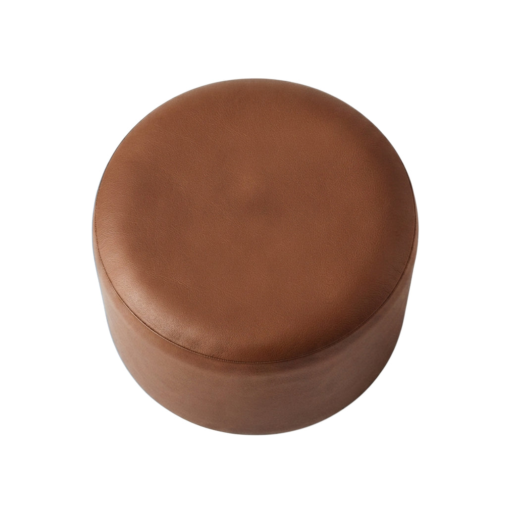 A round, low-profile ottoman upholstered in smooth medium-brown leather or faux leather, shown from a top-down perspective on a solid white background.