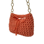 Peach crochet handbag styled on shoulder with gold chain strap