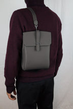 Person wearing a gray backpack on a plain background