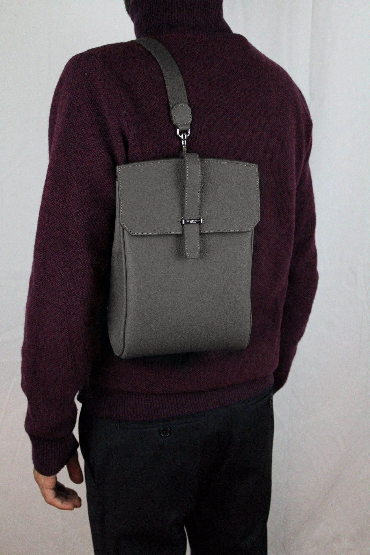 Person wearing a gray backpack on a plain background