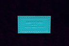 Turquoise leather label with embossed text on dark background, luxury Italian craftsmanship