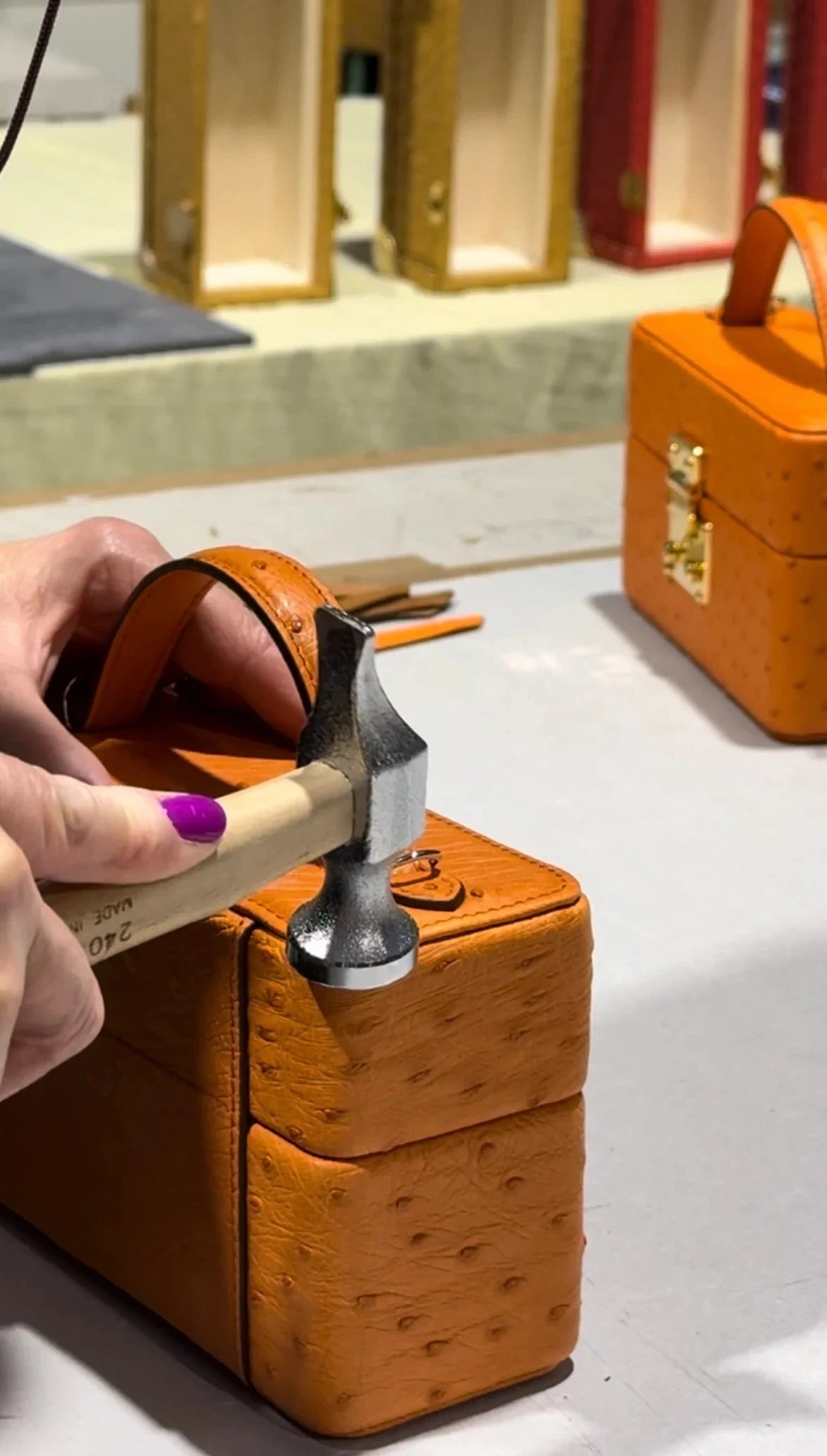 Person using a tool on an orange leather box