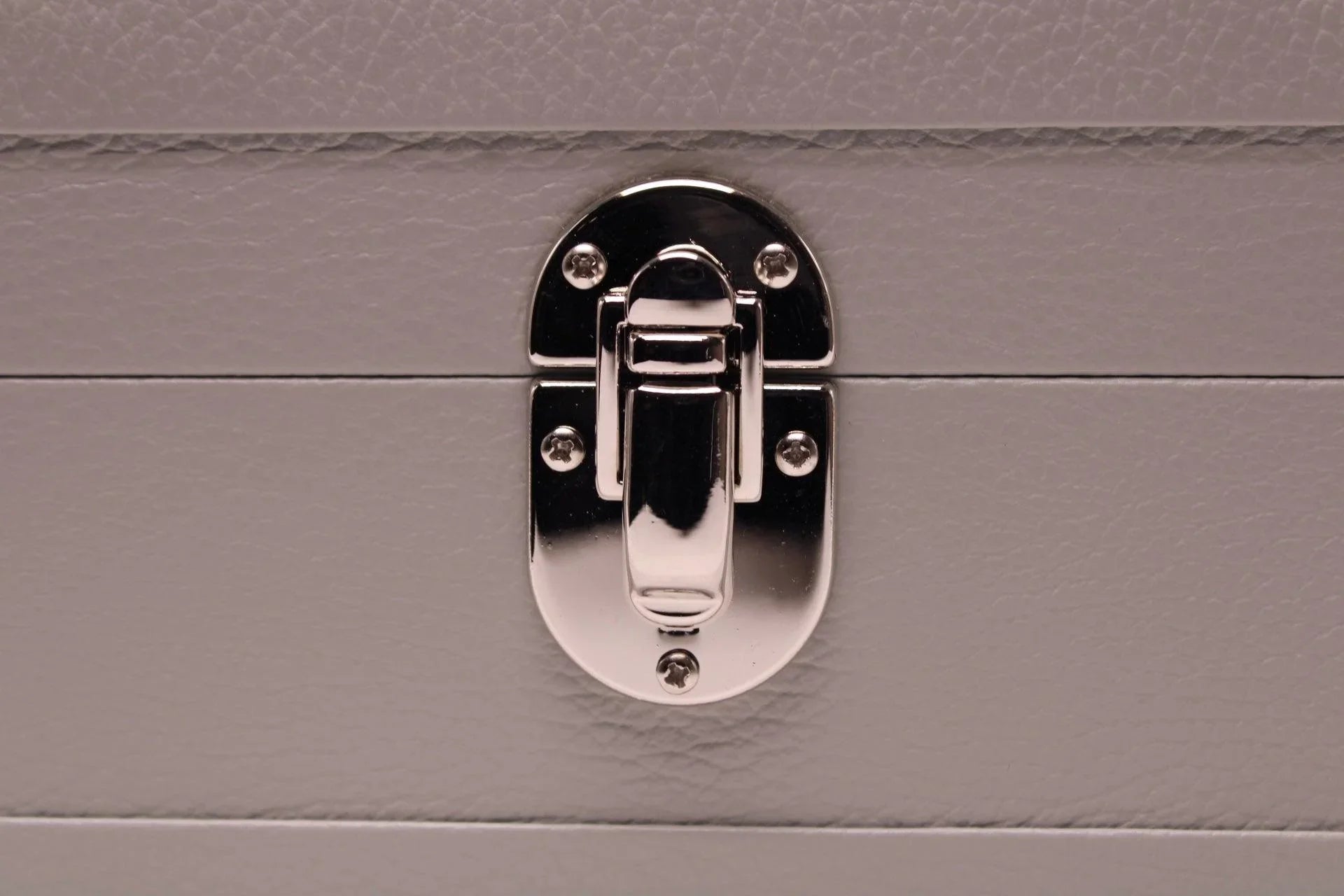Close-up of silver latch on textured grey leather box