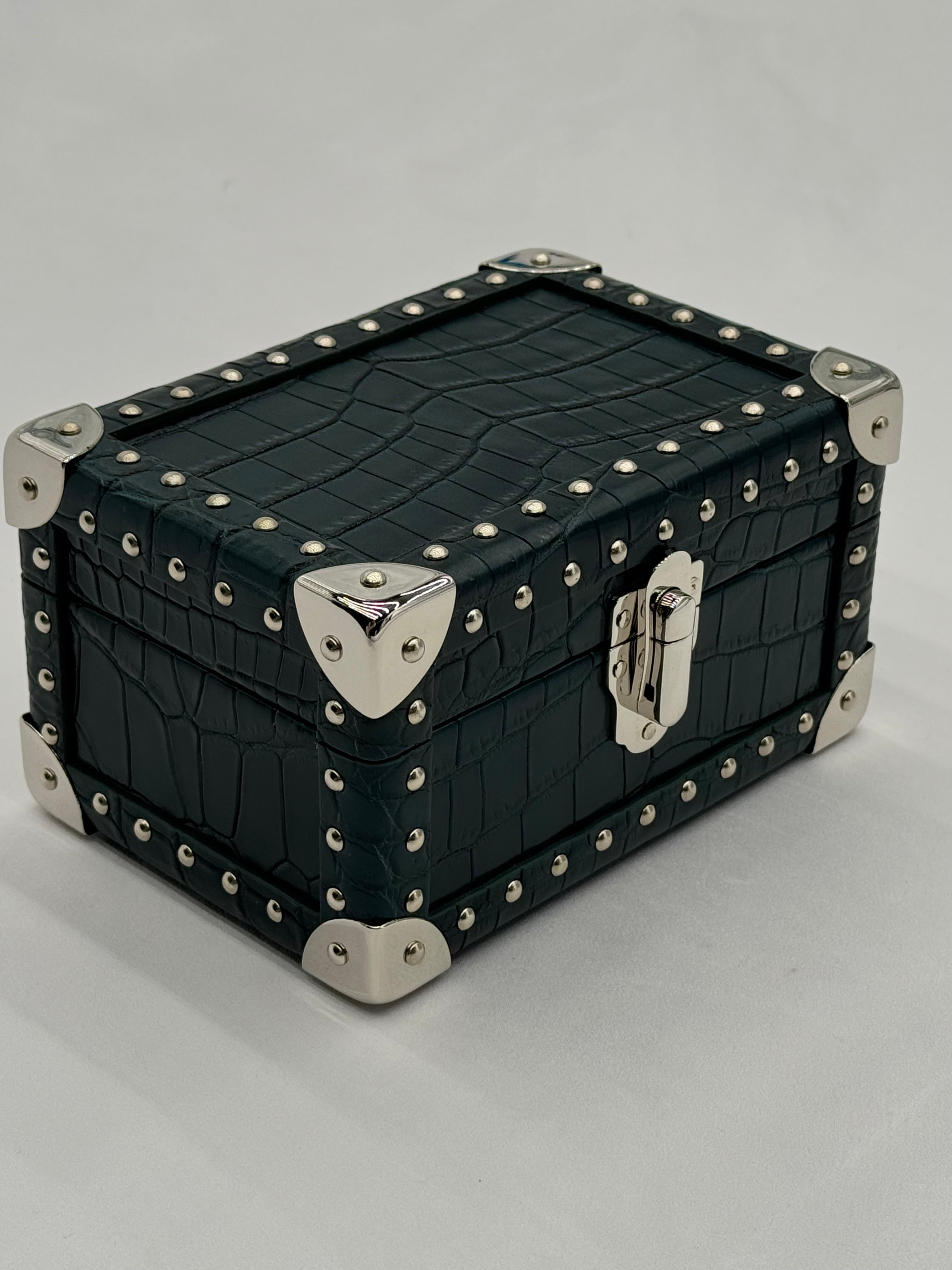 Black crocodile-patterned mini trunk with silver hardware on a gray background