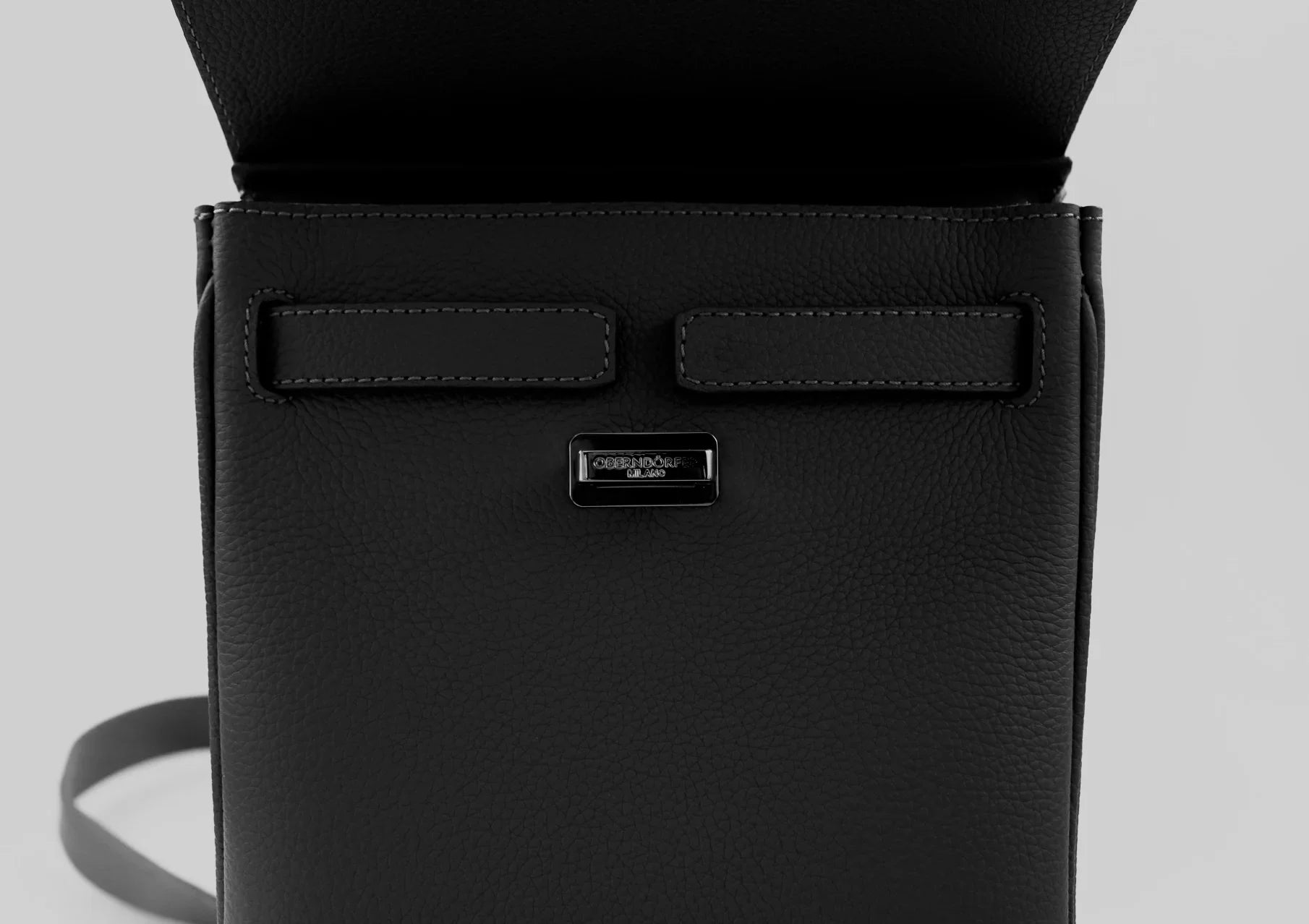 Black handbag with a visible brand logo on a light gray background