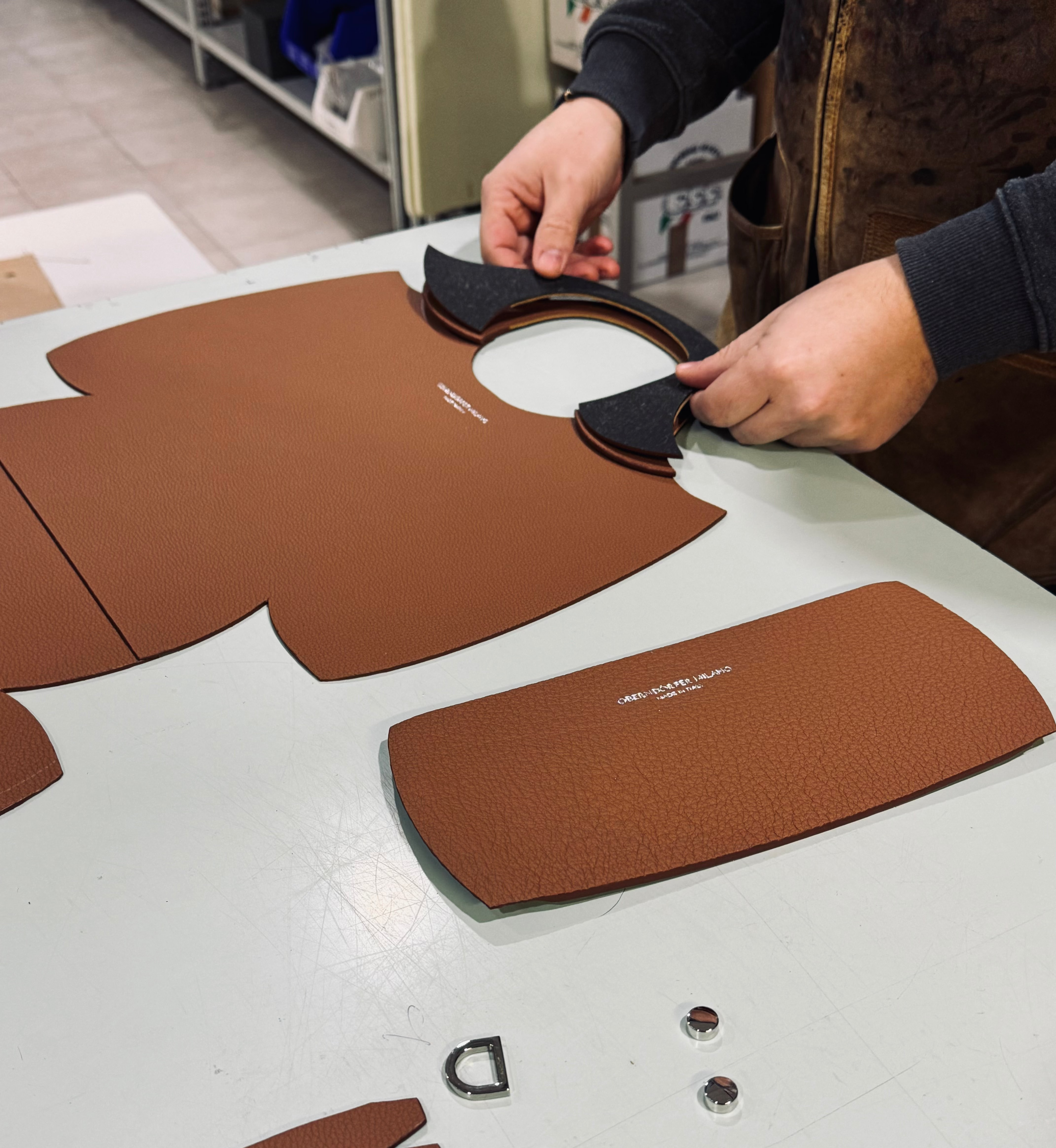 Person working with leather pieces and tools on a table
