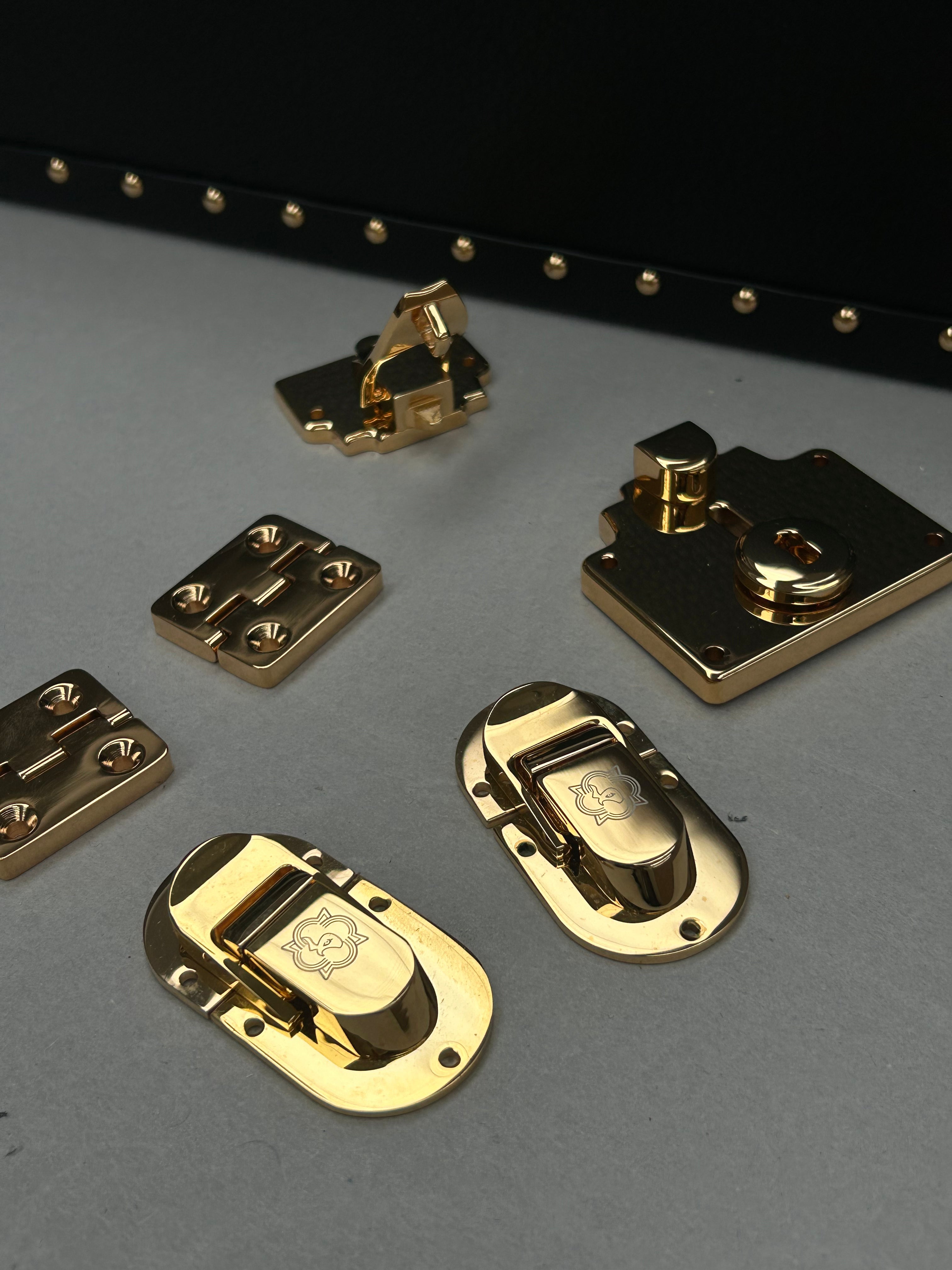 Gold metal latches on a gray surface with a black background