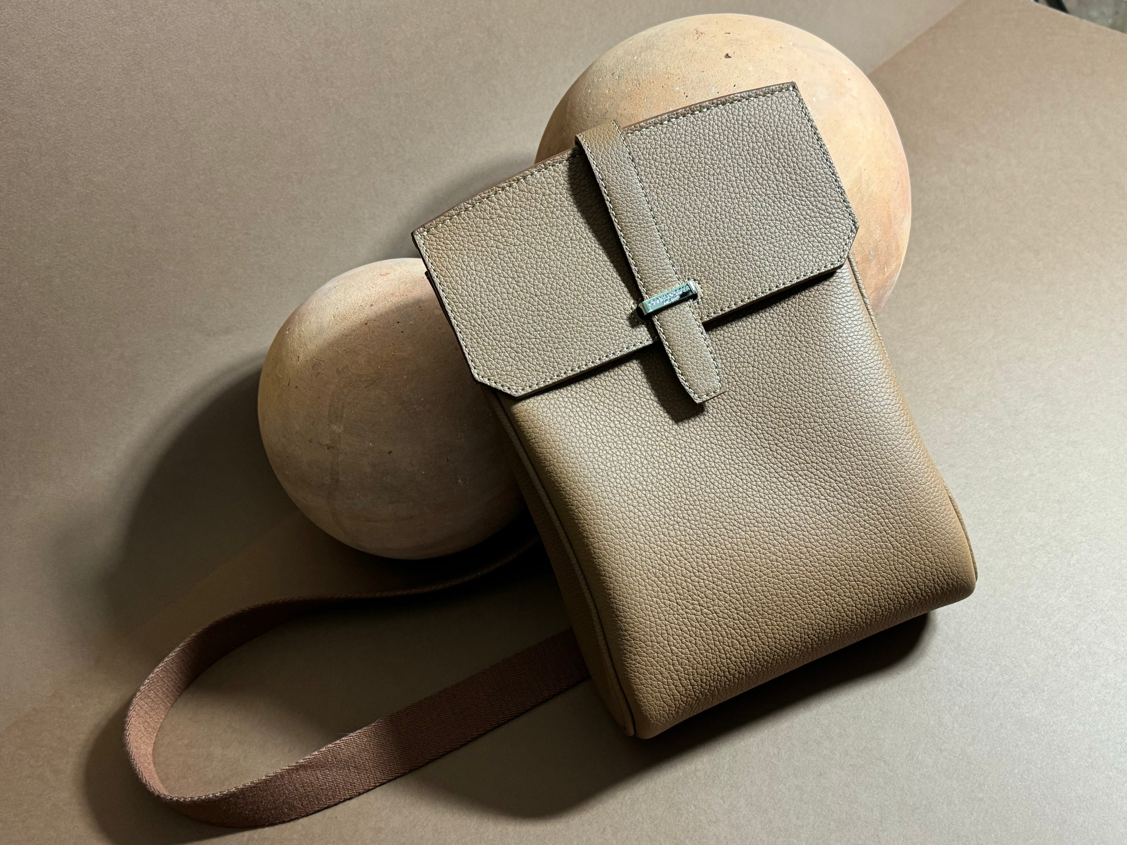 Beige leather handbag with a strap on a neutral background
