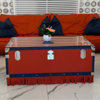 Orange and blue trunk used as a coffee table with an orange sofa and pillows in the background