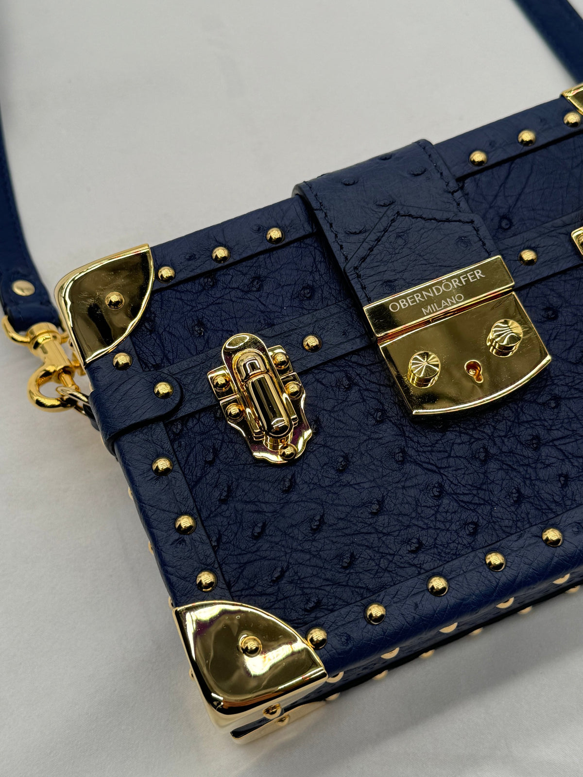 Navy ostrich leather trunk bag with gold Oberndörfer Milano hardware, close-up of craftsmanship