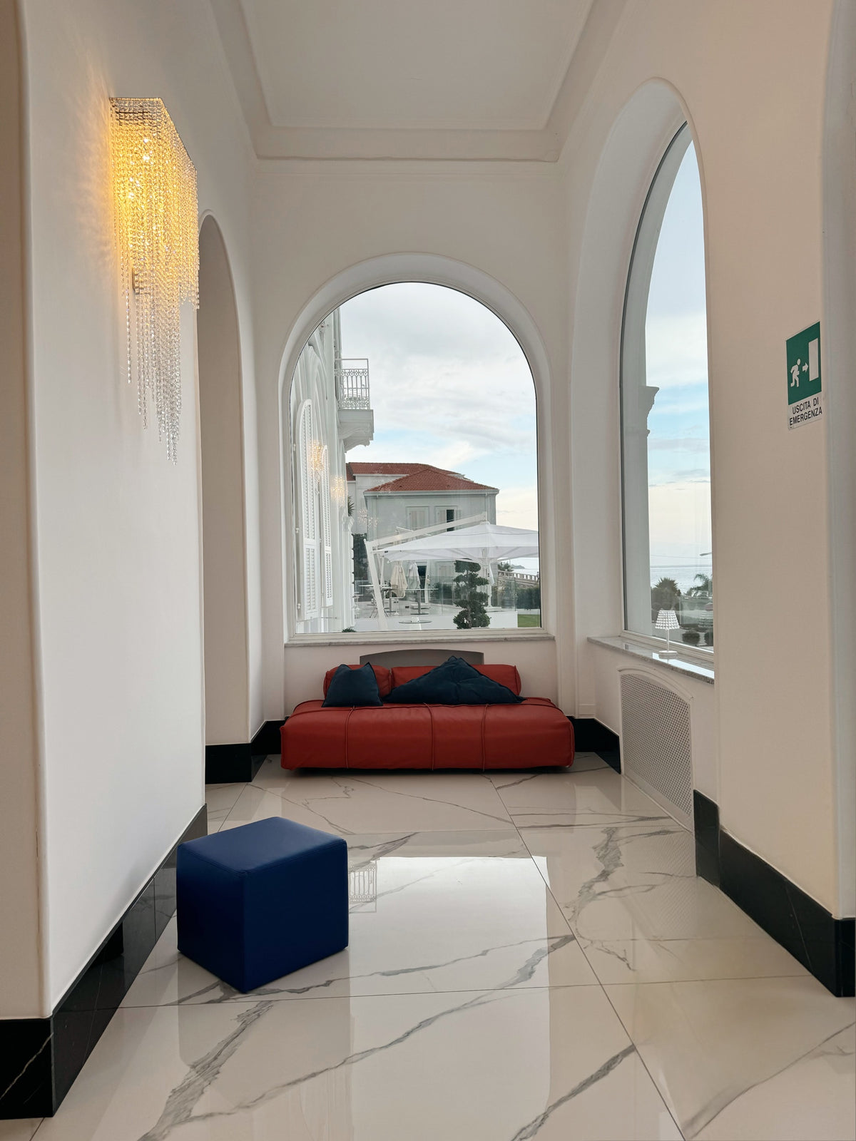 Blue leather cube pouf and red daybed in an arched gallery at the Miramare Palace