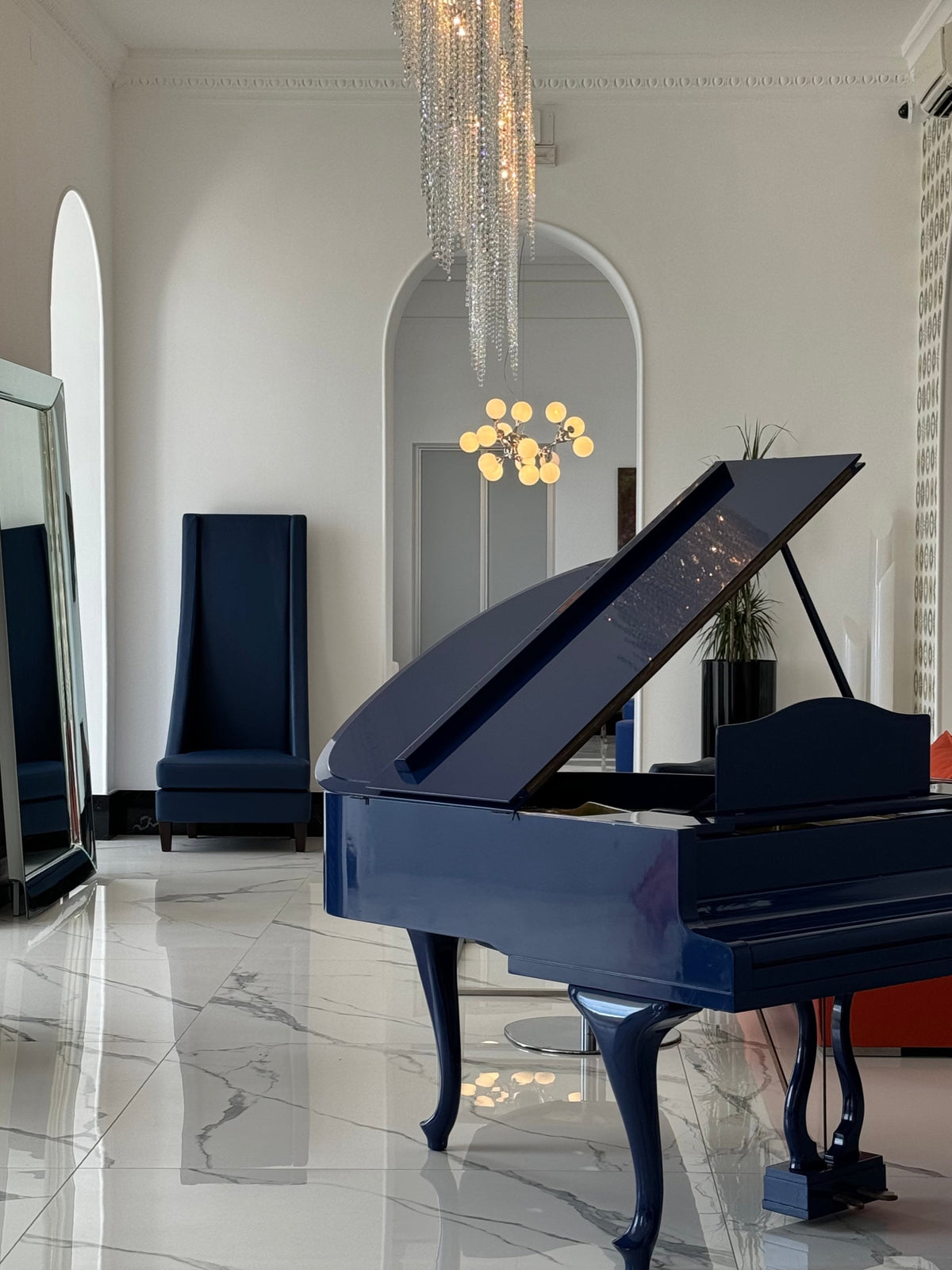 Navy leather high-back chair beside a grand piano in the Miramare Palace hall