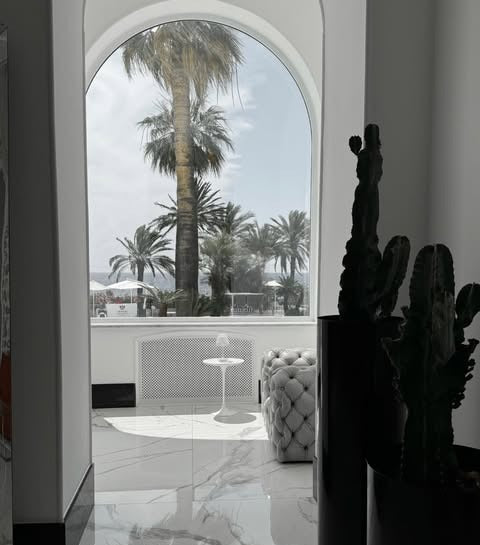 Arched window at Miramare The Palace Sanremo with palms outside, tufted poufs and marble floor