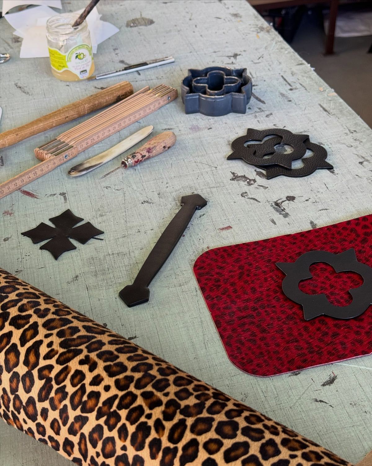 Leather pieces, tools and emblem cut-outs on the atelier bench