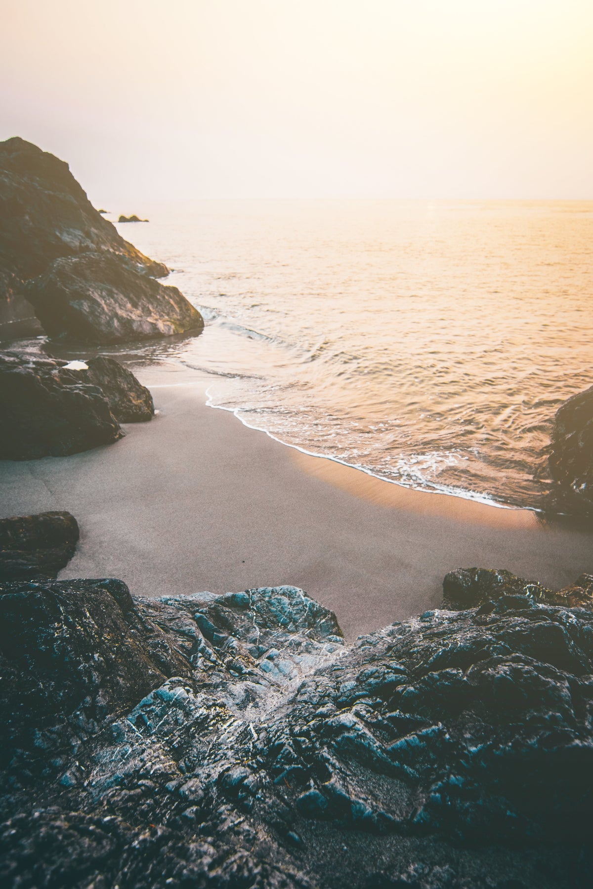 A quiet beach below cliffs, the sea lit by the sun